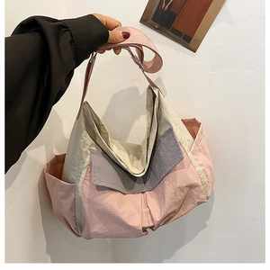 Detail of color-block nylon messenger bag in pink beige and grey with side pocket