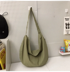 Macro detail of large olive green nylon crescent bag hanging on a white pegboard