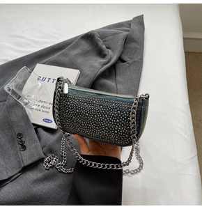 Detail of vintage blue denim handbag with silver studs and metal chain on grey blazer