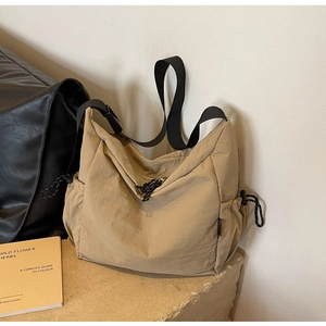 Detail view of khaki nylon crossbody bag featuring drawstring pockets and black strap