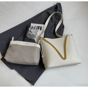 Close-up of white tote bag with gold chain strap and matching fabric pouch set