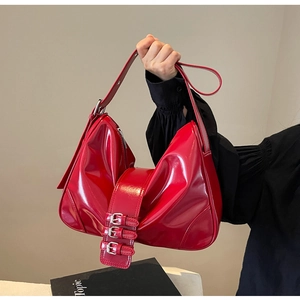 Detail of red patent leather hobo bag with three decorative metallic buckles
