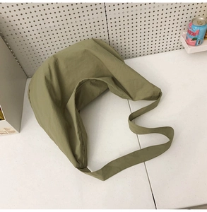 Detail of sage green nylon crescent bag showing soft fabric texture and wide strap
