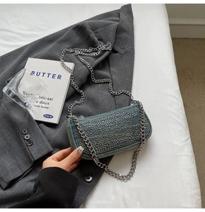 Detailed close-up of retro denim handbag featuring silver metal rivets and chain strap