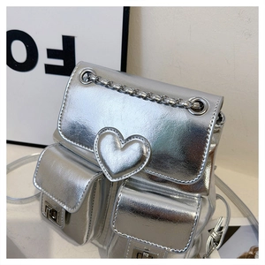 Close-up of silver metallic backpack featuring heart embossing and chain detail