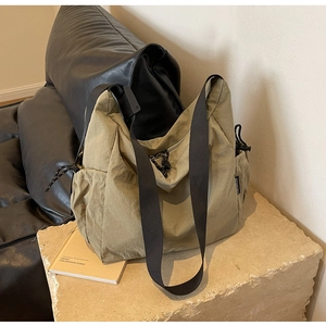 Detail of olive green nylon hobo bag with side drawstring pockets and wide strap