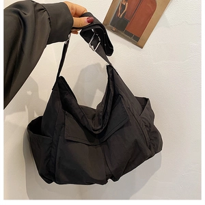 Detail of black utility messenger bag featuring multiple pockets and adjustable strap