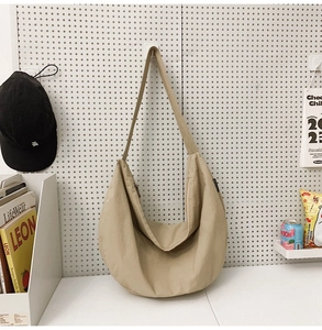 Detail view of beige nylon crescent bag featuring smooth zipper and wide shoulder strap