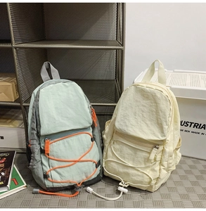 Dettaglio dello zaino in nylon verde chiaro con cordini elastici e tasche con cerniera