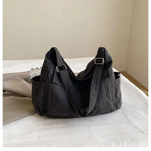 Close-up of black high-capacity canvas messenger bag with adjustable strap and side pocket