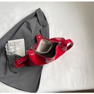 Detailed view of red patent leather shoulder bag with silver buckle and interior lining