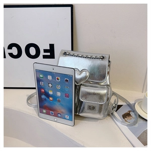 Mini silver backpack size comparison with a tablet showing heart detail and chain strap