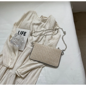 Detail of beige straw woven crossbody bag with silver bead trim and metallic chain strap