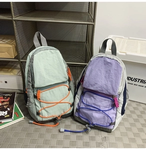 Dettaglio di mini zaini in nylon menta e lavanda con cordini elastici stile utility