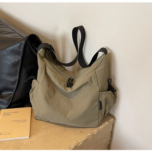 Detailed close-up of khaki nylon messenger bag with drawstring pocket and black strap