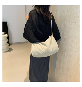 Detailoverzicht van een beige gewatteerde crossbodytas van zacht nylon met plooiontwerp