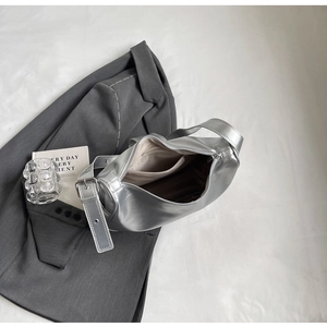 Close-up of metallic silver shoulder bag interior with zipper pocket on dark gray blazer