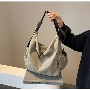 Close-up of khaki canvas tote bag with adjustable black strap and woven brand tag
