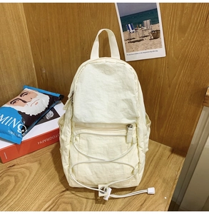 Dettaglio di uno zainetto in nylon crema con coulisse elastica e tasche laterali