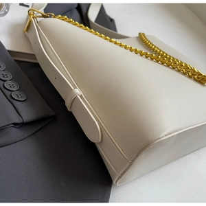 Detail view of cream tote bag with thick gold chain and smooth leather strap textures