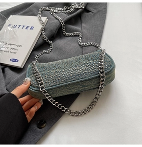 Detail of vintage denim shoulder bag featuring silver metal rivets and chunky chain strap