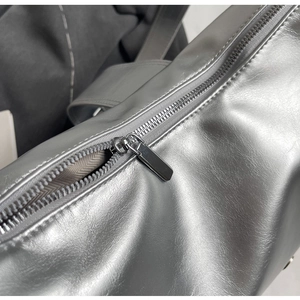 Close-up of metallic silver tote bag featuring a smooth silver zipper and beige lining
