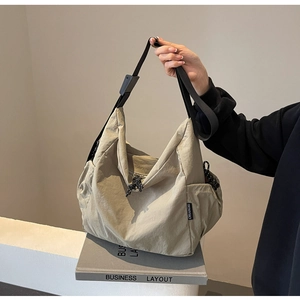 Detail of light khaki canvas bag with side drawstring pocket and adjustable black strap