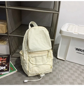 Dettaglio dello zaino in nylon crema con cordino elastico e tasca frontale esterna