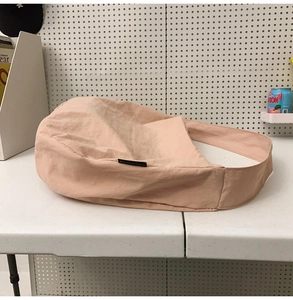 Detail of light pink nylon tote bag showing soft pleated texture and wide shoulder strap