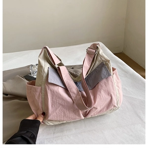 Detail of pink and beige patchwork nylon messenger bag with multi-pocket design