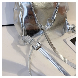 Detail of silver metallic bucket bag with pleated texture and adjustable chain straps