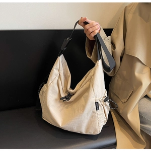 Detail of beige canvas tote bag showing the black CHUANGMI woven label and adjustable strap