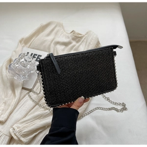 Detail of black woven crossbody bag with silver bead trim and metal chain strap