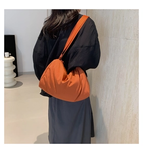 Caramel oranje nylon crossbodytas met brede schouderriem en een grote minimalistische inhoud