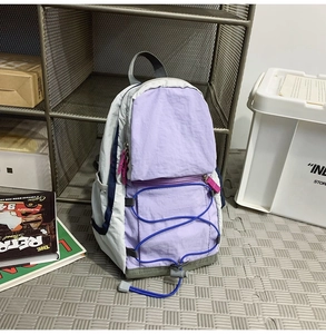 Dettaglio dello zaino da esterno in nylon leggero con cuciture viola e cordoncini blu elastici