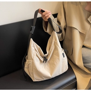 Detail of beige nylon crossbody bag with adjustable strap and side pocket storage