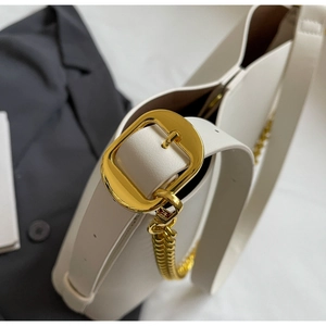 Detailed close-up of cream leather shoulder bag featuring stylish gold chain and square buckle