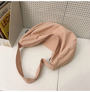 Macro view of minimalist nude pink nylon crescent bag with zipper and wide strap detail