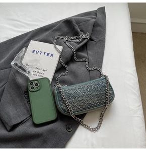 Detailed view of blue denim handbag with silver studs on a stylish grey suit jacket