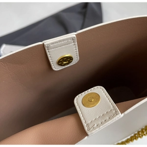 Detailed close-up of double magnetic gold clasps on a white leather tote bag interior