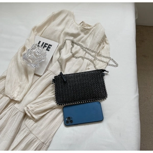 Detail of black woven straw phone bag with silver studs and metal chain strap