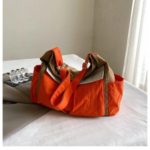 Detail view of large canvas crossbody bag with orange and khaki contrast stitching design
