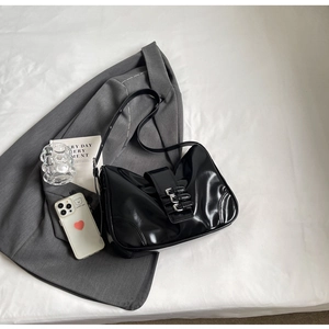 Detail of black glossy shoulder bag with silver metal buckles in a stylish lifestyle setting