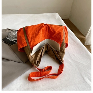 Detail of cargo canvas crossbody bag with contrast orange and brown panels and metal buckle