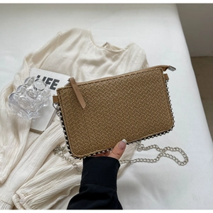 Detail of woven straw clutch with silver rivets and metallic chain strap for summer
