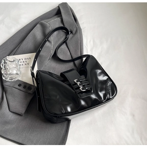 Detail of black glossy shoulder bag with silver buckles on white fabric background