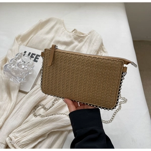 Close-up of woven straw crossbody bag with silver bead trim and metal chain strap