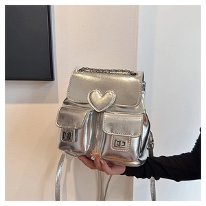 Detail of silver metallic backpack with heart-shaped buckle and chain handle
