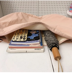 Detailed internal storage of pink nylon tote showing notebooks and accessories
