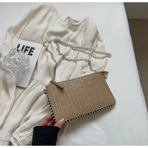 Detail of woven straw shoulder bag featuring silver bead trim and a sleek chain strap